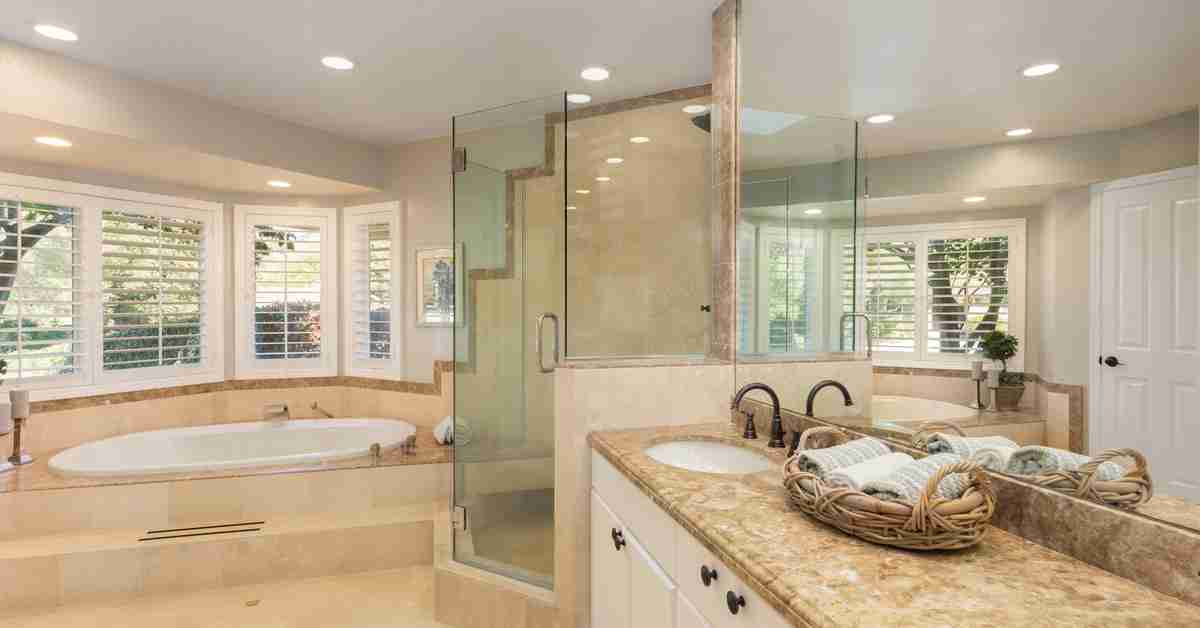 A spacious bathroom with a double sink, a glass walk-in shower, a luxurious bathtub, and ample counter and cabinet space.