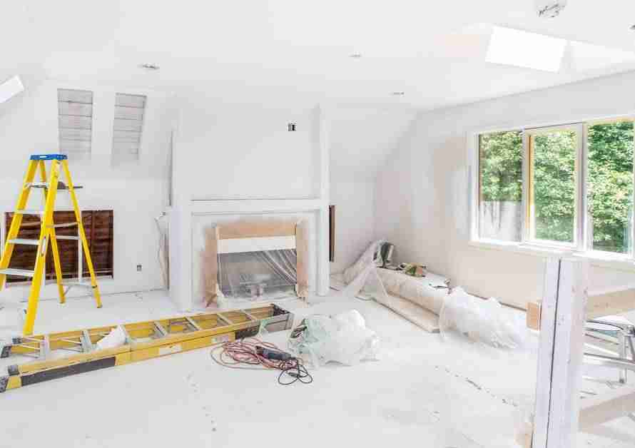 A living room that is currently being remodeled. The room is full of construction equipment, including two ladders.